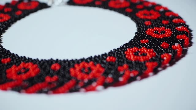 Stylish red and black necklace against white backdrop. Ukrainian Elegant accessory with red and black beads on white. Contrast of colors in beaded necklace on white. Red and black beads in necklace on clean white. Beautiful pattern and ornament