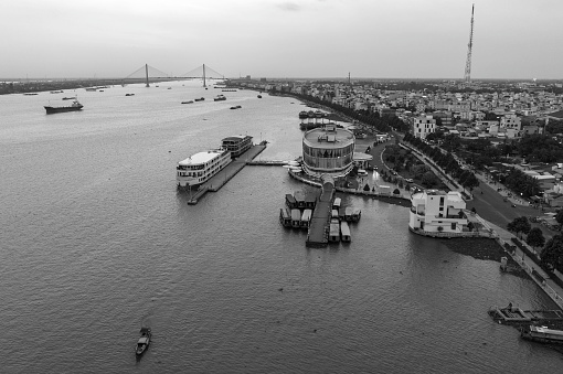 Industrial pier with floating docks on the Columbia River, moored river tugs, cranes for unloading and loading barges on one side and floating houses on the other side of the river and a drawbridge