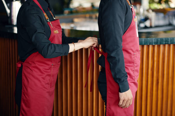 istock Waitress Helping Coworker to Tie Apron 2145924004