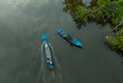 Aerial photo of Vietnamese farmers casting nets to catch fish on a small canal one afternoon in Ca Mau province. Ca Mau has an intricate river system with many aquatic resources. That condition helps people earn extra income and food outside of working hours.