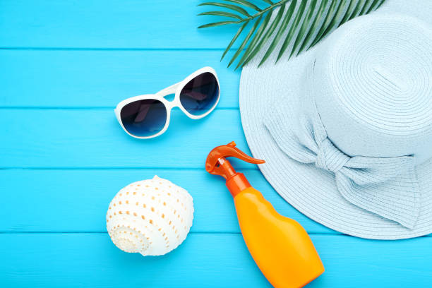 istock Summer straw hat with palm leaf, sunglasses, conch and moisturizing cream on blue wooden table 2145929355