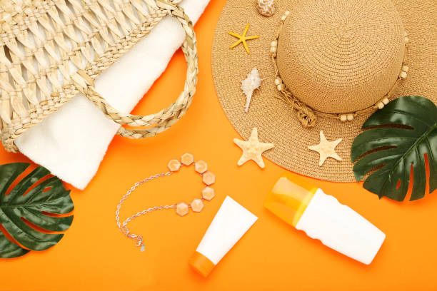 istock Summer straw hat with monstera leafs, seashells and moisturizing creams on orange background 2145935561