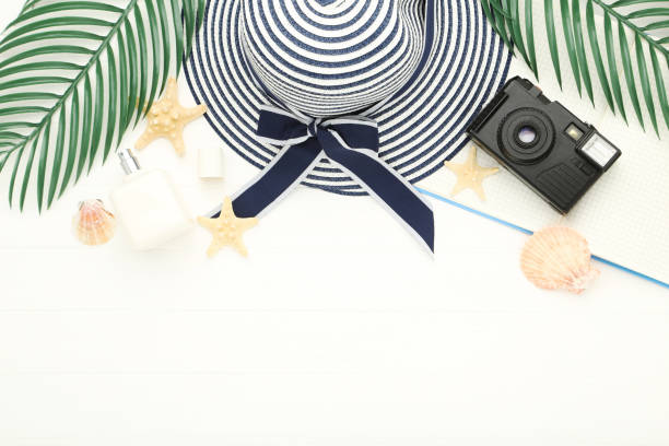 istock Summer straw hat with palm leafs, seashells, notepad and retro camera on white wooden table 2145942890