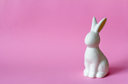 Ceramic Easter bunny on pink background, Easter minimalism concept with copy space