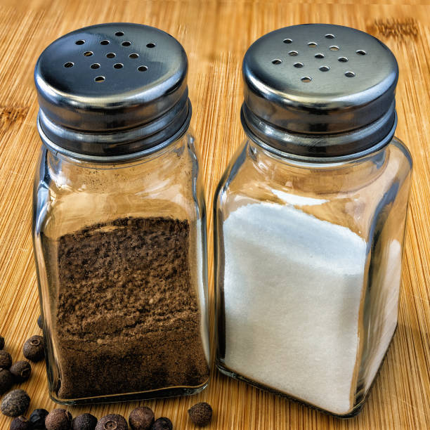 for kitchen spices - two glass containers with pepper and salt on a bamboo cutting board