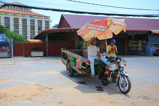 unidentified local people sit on the motor waiting someone. Phnom Penh is the capital of cambodia.