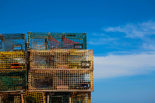 A pile of lobster traps against a vivid blue sky in Maine, USA.