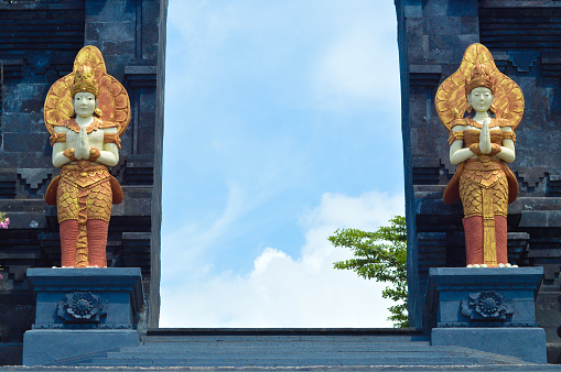 Low Angle View Of Male And Female Guardian Statue In Front Of The Entrance Gate To Main Area Of Buddhist Temple At Banjar Tegeha, Buleleng, Bali, Indonesia