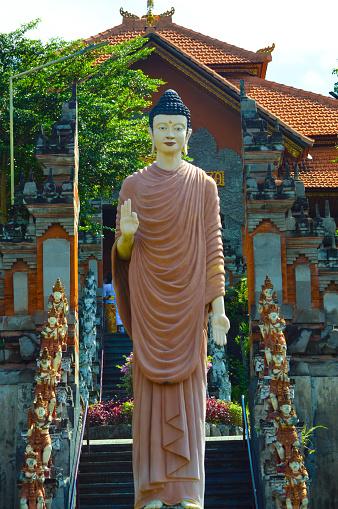 Portrait Front View Of A Buddha Monk Statue Standing In A Blessing Pose In Front Of Building At Brahmavihara-Arama, Banjar Tegeha, Buleleng, Bali, Indonesia