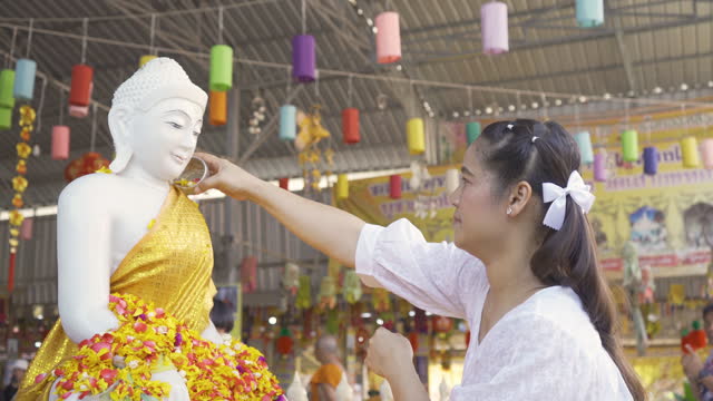 Beautiful Asian girl bathes Buddha image on Songkran day, Thai New Year.