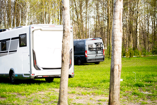 Camper Van during green camping in the park for motorhomes. Traveling in a camper has recently become more popular, for some it has become a lifestyle, and even some young people are selling their home, exchanging the stay-at-home lifestyle for sightseeing and long holidays. \nCaravaning is one of the forms of motor tourism in which a camping trailer or a camping car serves as a food and accommodation base. The caravanning movement was organized into an organized club framework in England at the beginning of the 20th century.