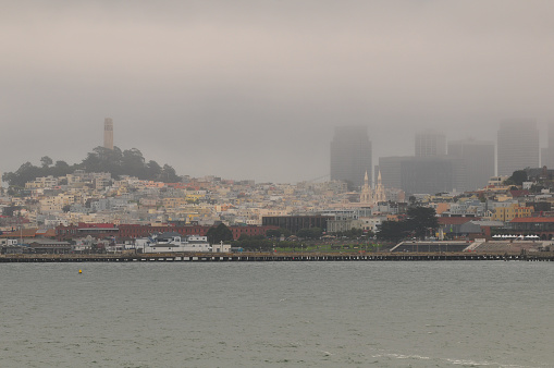 A foggy view of Telegraph Hill, the Coit Tower and Downtown district from the bay, San Francisco, California, USA.