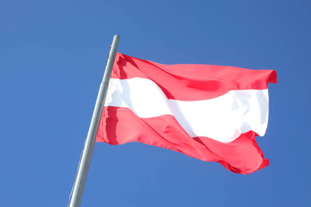 istock Large Austrian flag in white and red colors waving against a cloudless blue sky 2146226724
