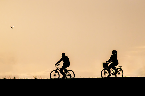 backlit silhouette of person riding a bicycle at sunset