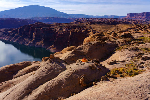 Lake Powell Scenic Overlook with Backpacking Tent - High angle view overlooking scenic Lake Powell and red rock formations and a labyrinth of canyons. Tent on edge of canyon rim backpacking scenic landscape.