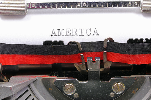 Typewritten AMERICA text in black ink on white paper with an antique typewriter