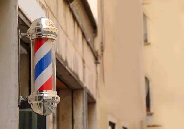 rotating barber shop sign with spiral stripes outside a traditional business in the city