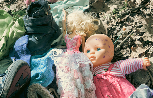 Baby doll, shoes and other children's things abandoned in nature.