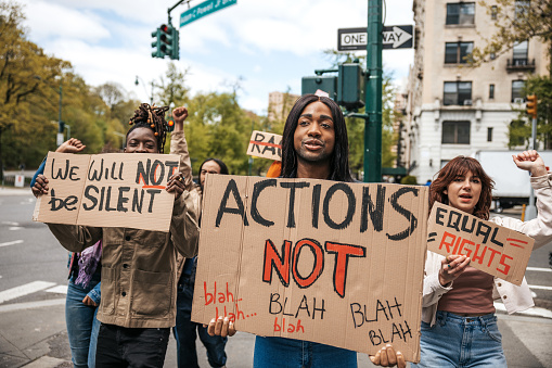 Group of young adult men and women marching together on strike against racism holding signs on cardboards for equal rights for everyone. Rally in New York City.