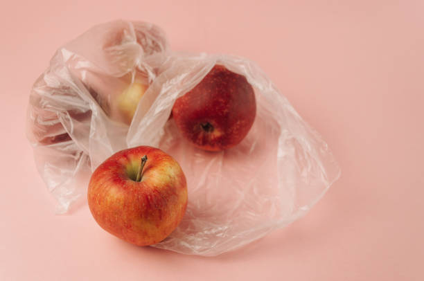 istock Three apples are in plastic bags on a pink background 2146381939