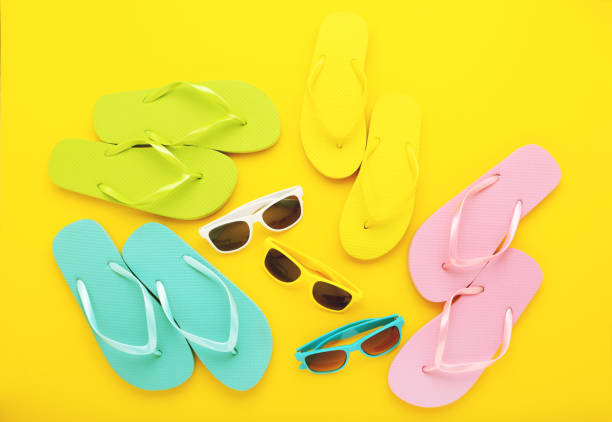 istock Colorful flip-flops with sunglasses on yellow background 2146423467