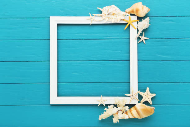 Starfishes with seashells and photo frame on blue wooden table