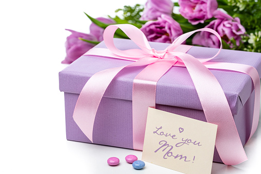 Mother's Day concept with purple gift box, candies and tulips on white background. High resolution 42Mp studio digital capture taken with Sony A7rII and Sony FE 90mm f2.8 macro G OSS lens