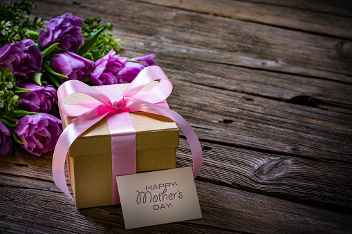 Mother's Day design concept background with tulips and gift on wooden table. Copy space. High resolution 42Mp studio digital capture taken with Sony A7rII and Sony FE 90mm f2.8 macro G OSS lens
