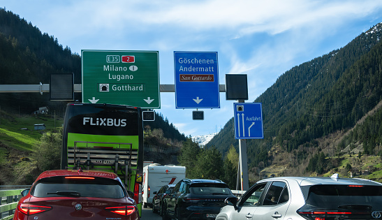 Goschenen, Switzerland - April 6, 2024: Vehicles standing in a queue in front of the Gotthard motorway tunnel. Flixbus bus transport company.