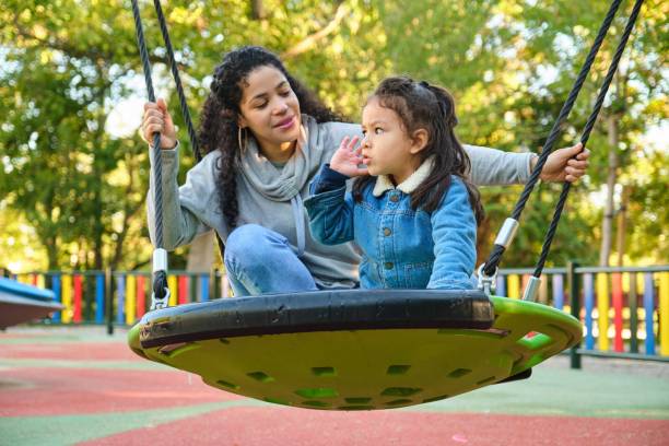 istock Latin mother playing with her son on a swing in a park. 2146468831