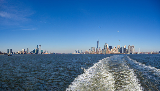 Panoramic view of New York City from the free State Island Ferry cruising the Hudson River. Manhattan and Jersey skyline from water and cruise foam. Copy space
