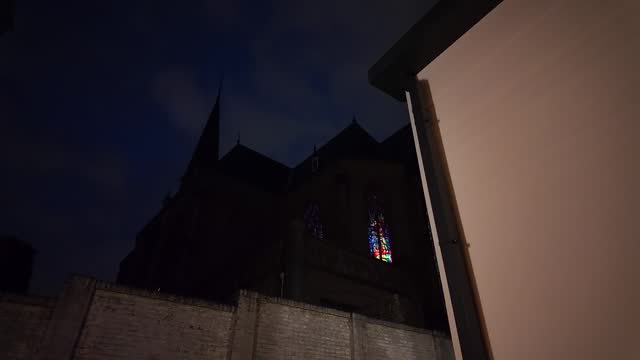 Silhouette of catholic church at night with blue dark sky and white wall