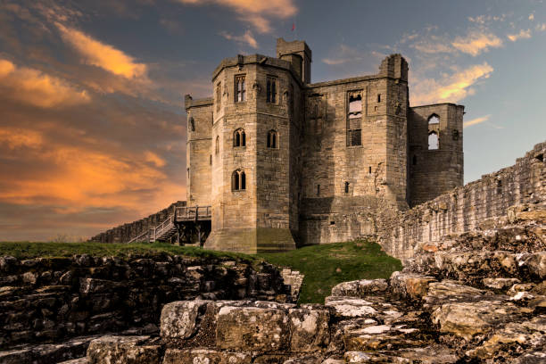 le donjon fortifié en forme de croix du château de warkworth dans le northumberland, au royaume-uni, au coucher du soleil - warkworth castle photos et images de collection