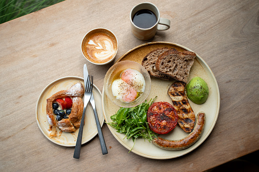 A big breakfast set with Americano and hot latte, served on a wooden table background