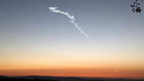 A bright contrail left behind by SpaceX's Falcon 9 rocket that launched from Vandenberg Space Force Base over 200 miles away. The Falcon 9 rocket carried 21 new Starlink satellites to low-Earth orbit.