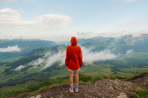 Woman in red coat with good hiking on mountain ridge Augstmatthorn in Swiss Alps in summer