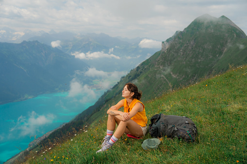 Woman sitting on the meadow looking at view of Brienz lake in Swiss Alps and enjoying tranquility