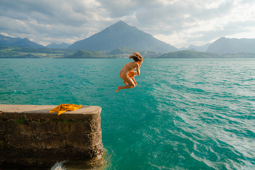 Woman jumping into the lake in Swiss Alps  to swim in summer