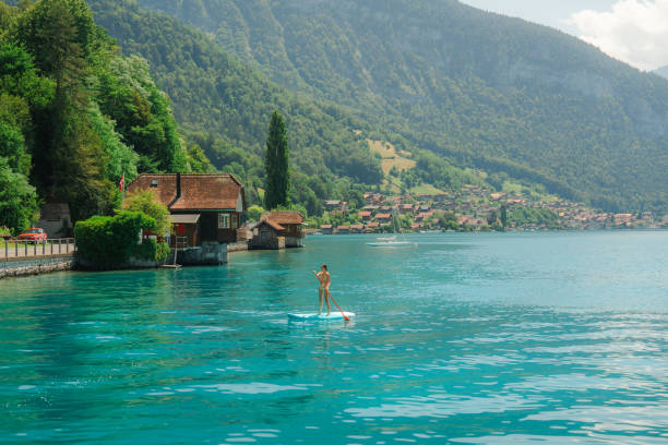 Serene scene of woman SUP boarding on lake in Alps in summer