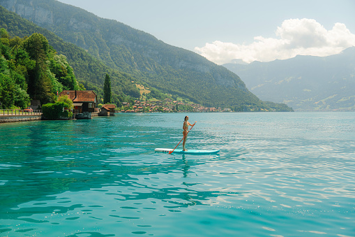 Serene scene of woman SUP boarding on lake in Alps in summer