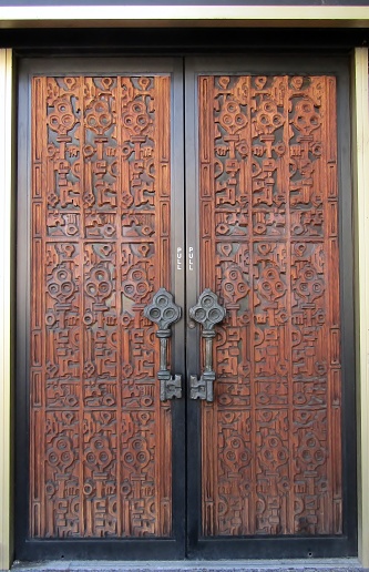Old wooden door adorned with key-shaped ornaments and featuring key handles, located in Olympia, WA, USA