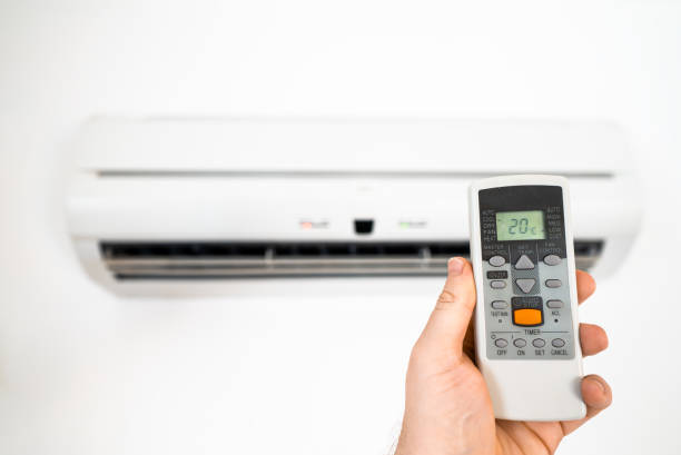 istock Hand holding remote control in front of the air conditioner. 2146633922