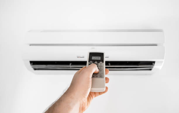 istock Hand holding remote control in front of the air conditioner. 2146633923