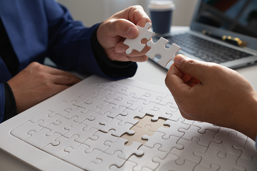 In hands of businessmen and investors they hold jigsaw pieces to put together in right way to make the jigsaw pieces symbolize their participation in business ventures. Venture capital symbol concept