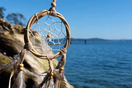 An image of a handmade dreamcatcher with the blue Pacific Ocean in the background.