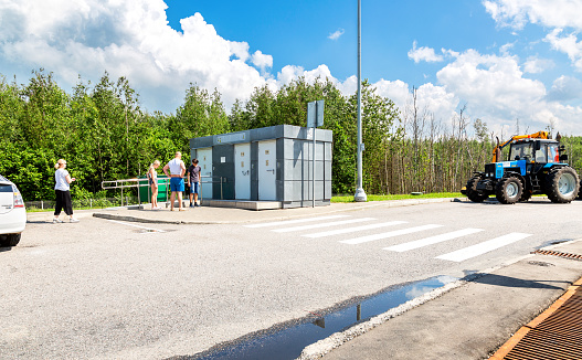 Moscow region, Russia - July 12, 2022: People stand in a queue near the public toilet on the parking lot of highway number M11 in summer day