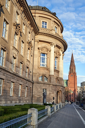 Classicist public building and tower of a neo-Gothic church on a street in the city center of Poznan, Poland