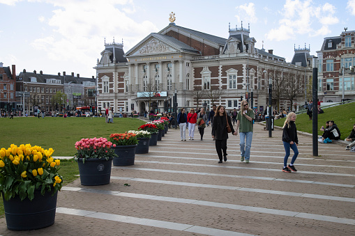 Amsterdam, Netherlands, April 7, 2024; People walk on the museum square with the Royal Concertgebouw in the background in Amsterdam.