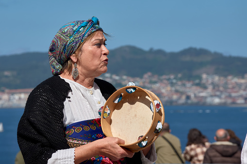 Vigo, Pontevedra, Spain; April 7, 2024; a tambourine singer sings with the Vigo estuary in the background during the Reconquest of Vigo festival