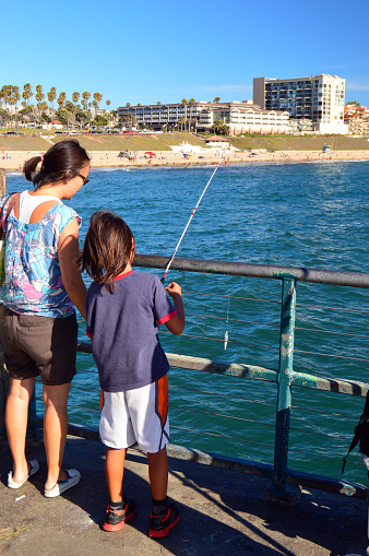 Redondo Beach, CA, USA July 23 A mother and daughter spend the day fishing from a pier into the ocean at Redondo Beach, California